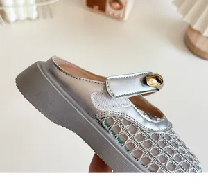Gros plan de mules en maille argentée pour enfants avec bride velcro et perle dorée.