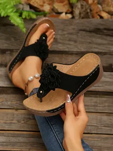 Detailed view of women's black wedge thong sandals featuring a stylish 3D flower ornament