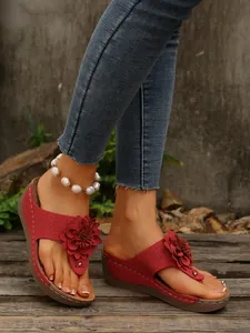 Detailed shot of elegant red floral wedge thong sandals featuring a pearl anklet accent