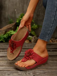 Detail shot of women's red wedge sandals featuring a 3D flower and open-toe design