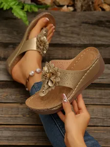 Detailed view of champagne wedge sandals featuring large 3D flower and laser-cut patterns