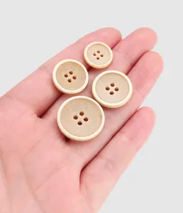 Close-up detail view of premium urea clothing buttons in four different sizes held in hand