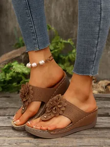 Detail view of brown wedge flip-flops featuring 3D flower decor and breathable upper