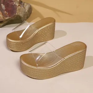 Gros plan sur des sandales dorées à semelles compensées et brides transparentes