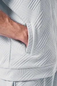 Close-up detail of men's light grey textured jacquard jacket featuring a functional zip pocket