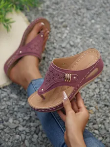 Macro view of mauve wedge thong sandals with laser-cut patterns and metallic rivets