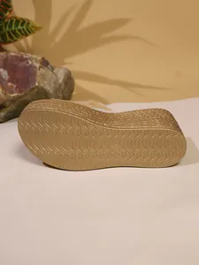 Détail de la semelle compensée dorée avec texture ondulée antidérapante et marquage de taille
