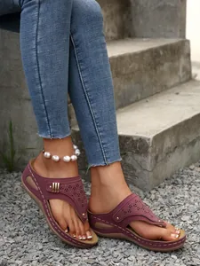 Close-up shot of plum wedge flip-flops showcasing delicate laser-cut patterns and gold rivets
