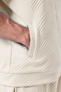 Macro view of the intricate jacquard weave and pocket detail on a men's casual beige jacket