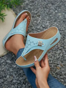 Detail view of light blue wedge thong sandals with laser-cut patterns and rivet accents