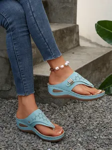Detailed close-up of light blue wedge thong sandals with laser-cut patterns and studs