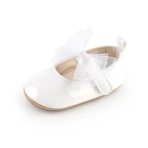 Primer plano de zapatos de princesa blancos para bebé con un gran lazo de malla