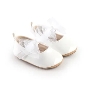 Detalle de zapatos blancos de princesa para bebé con un elegante lazo de malla