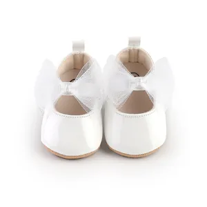Vista detallada de zapatos de princesa para bebé en charol blanco con lazos de malla