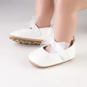 Primer plano de zapatos blancos de princesa para bebé con lazos de malla decorativos