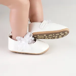 Detailopname van witte baby prinsessenschoenen met een kanten strik met stippen.