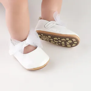 Detalle de zapatos de princesa de charol blanco para bebé con un gran lazo de malla