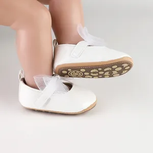 Primer plano de zapatos de princesa blancos para bebé con lazo de malla y brillo