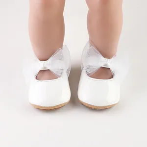 Detalle de zapatos blancos de princesa para bebé niña con un delicado lazo de tul