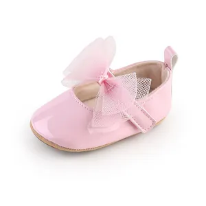 Detalle lateral de un zapato de princesa para bebé en charol rosa con lazo grande