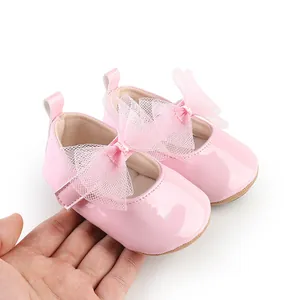 Detalle de zapatos de princesa para bebé en color rosa con lazos de malla y acabado brillante