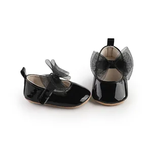 Detalle de zapatos de charol negro para bebé con un elegante lazo grande de malla.
