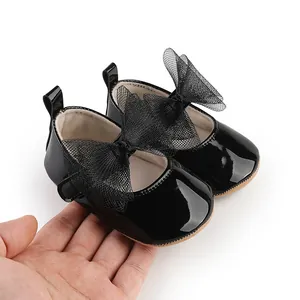 Vista detallada de zapatos de princesa en charol negro con lazo grande de red