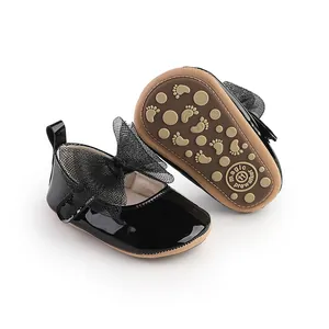 Detalle de zapatos de bebé niña en charol negro con un elegante lazo decorativo de malla