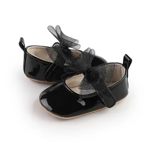 Vista detallada de zapatos para bebé en charol negro con elegantes lazos de malla.
