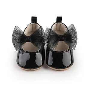 Primer plano de zapatos de charol negro para bebé con grandes lazos de malla