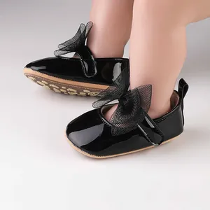 Primer plano de zapatos de princesa para bebé en charol negro con lazo de malla.