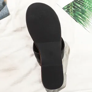 Close-up detail van de antislipzool met textuur van een zwarte platte teenslipper.