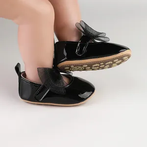 Vista detallada de zapatos de charol negro para bebé niña con un gran lazo de malla