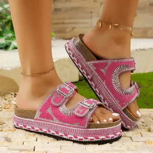 Close-up view of pink platform sandals with sparkling rhinestone buckles and cork soles.