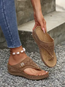 Stylish brown wedge thong sandals featuring laser-cut patterns and metal rivet details