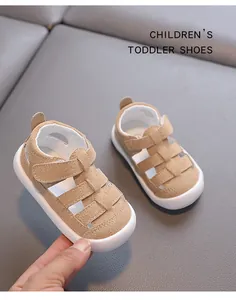 Close-up of tan suede toddler sandals with hollow design and white soft anti-slip soles.