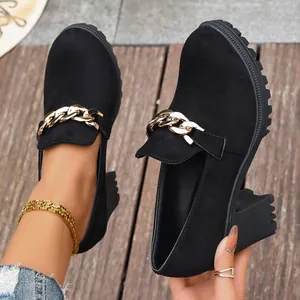 Λεπτομέρεια από μαύρα loafers με χοντρό τακούνι και κομψή χρυσή αλυσίδα διακόσμηση