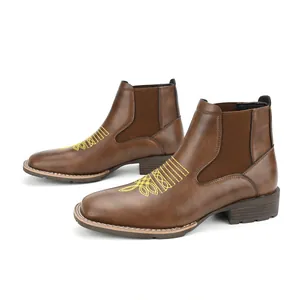 Gedetailleerd aanzicht van bruine Chelsea boots met geel borduursel en elastiek