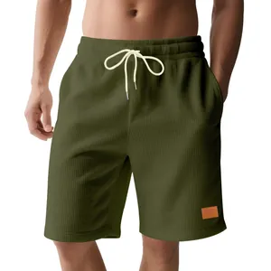 Dettaglio di pantaloncini da uomo in velluto a coste verde oliva con trama a nido d'ape.