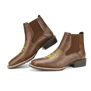 Detail van bruine heren Chelsea boots met gele decoratieve borduursels op de neus van de schoen