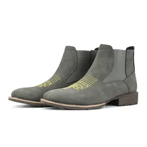 Detailoverzicht van grijze suède Chelsea boots met geel borduursel op de neus