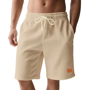 Dettaglio di pantaloncini beige in velluto a coste da uomo con coulisse e texture.