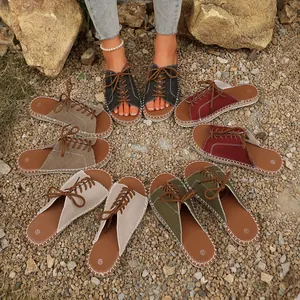 Display of various colored women's lace-up flat canvas slippers on gravel ground