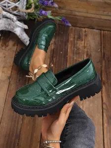 Dettaglio dei mocassini verde scuro goffrati coccodrillo con suole platform nere spesse