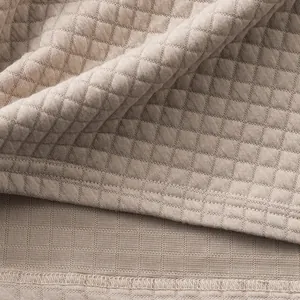 Nahaufnahme der schweren Jacquard-Stoffstruktur und Nähte am beigen Herren-Poloshirt.
