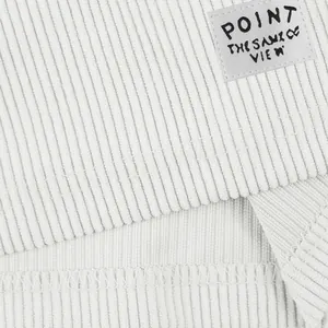 Gros plan sur la texture du velours côtelé blanc et l'étiquette sur le short homme.