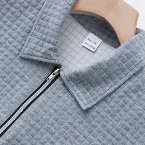 Detailansicht eines grauen Herren-Poloshirts mit Waffelstruktur, Reißverschluss und XL-Etikett
