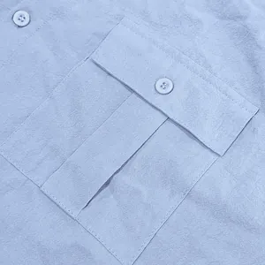 Close-up detail of men's linen shirt pocket with buttoned flap and textured fabric