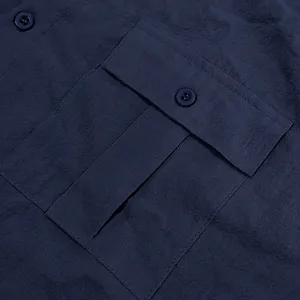 Macro detail of a navy blue casual linen shirt showing the chest pocket and button flap