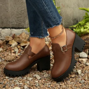 Λεπτομέρεια από καφέ γυναικεία loafers με πλατφόρμα, χοντρό τακούνι, αγκράφα και σόλα.